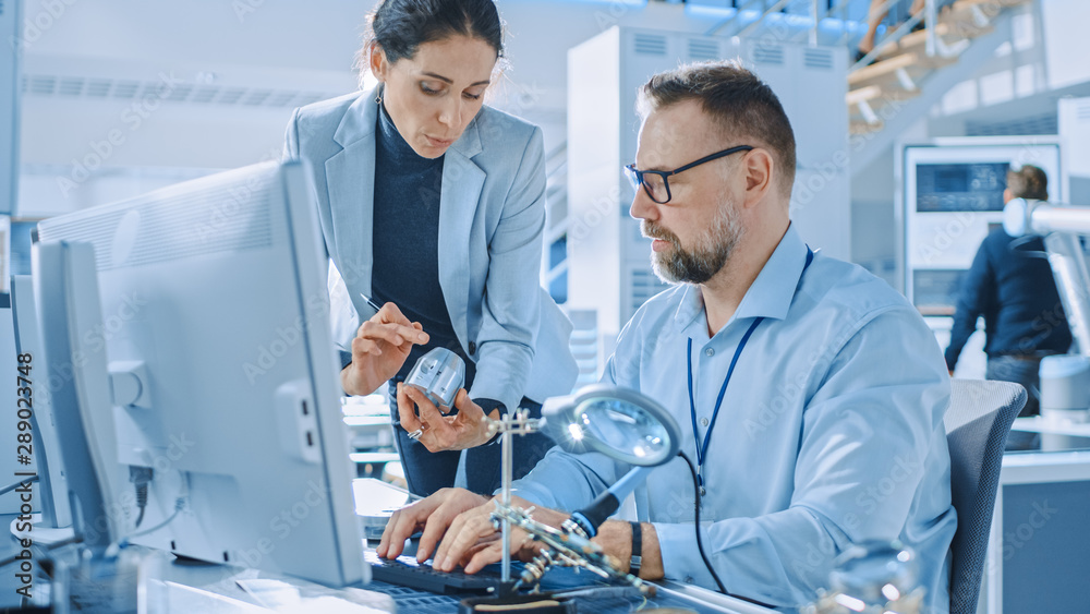 Female Industrial Engineer Talks with Electronics Specialist, She Holds Metal Component Prototype, h