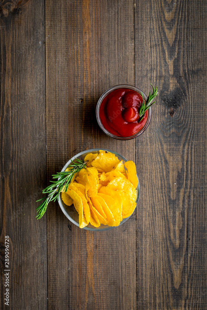 Potato chips served wiith ketchup on wooden background top view