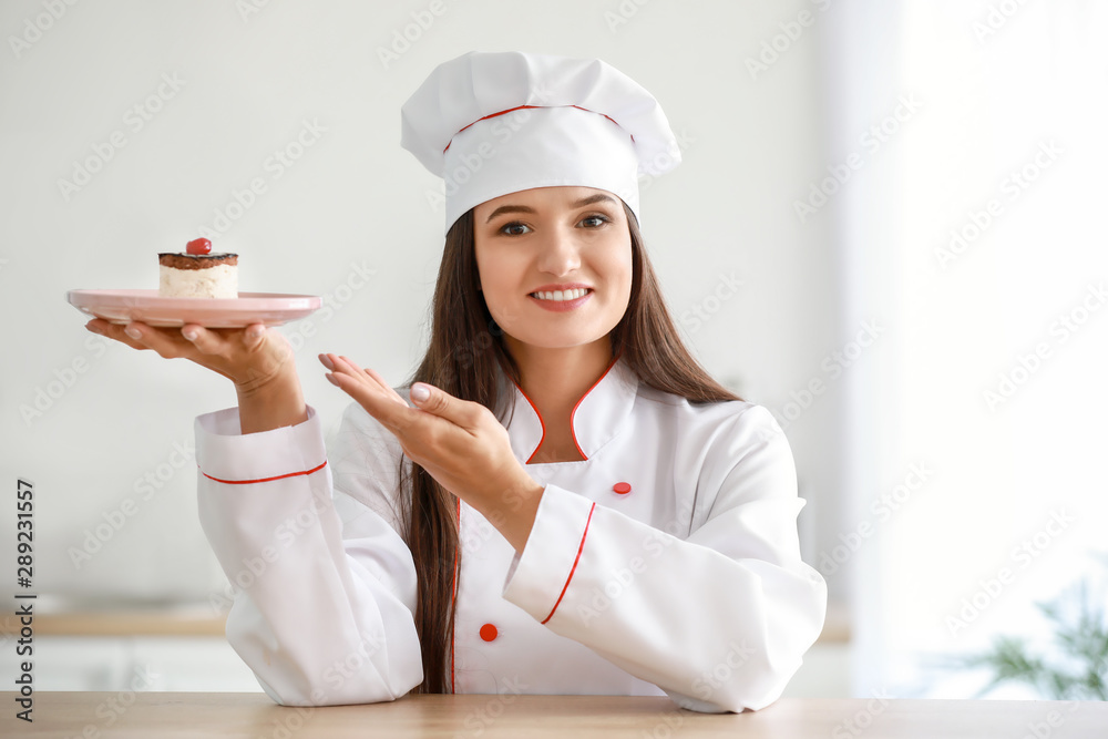 Beautiful female chef with tasty cake in kitchen