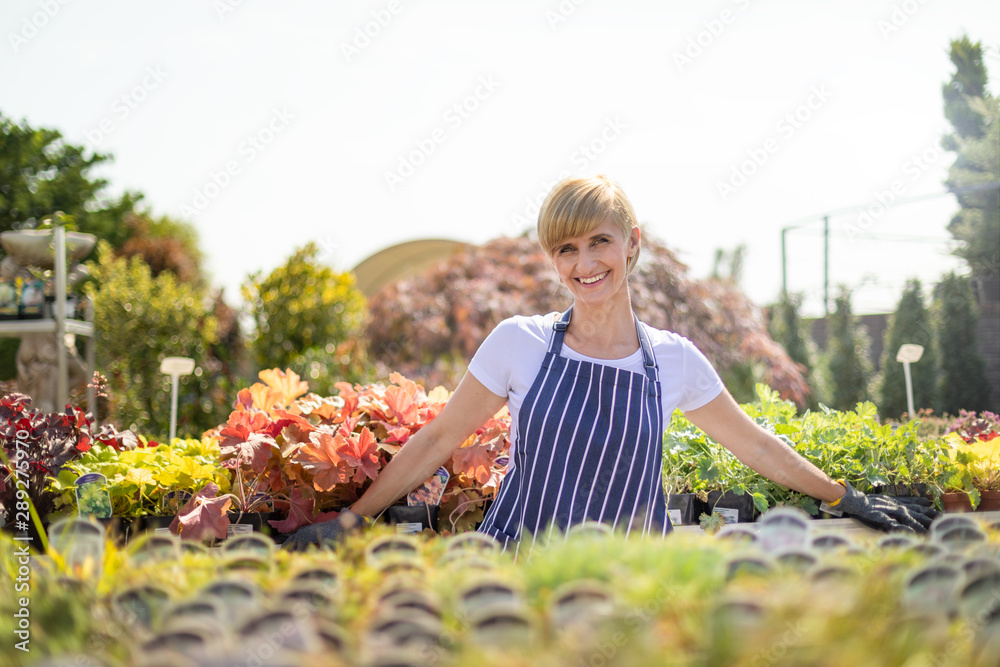 Smiling gardener woman who is employee in garden center