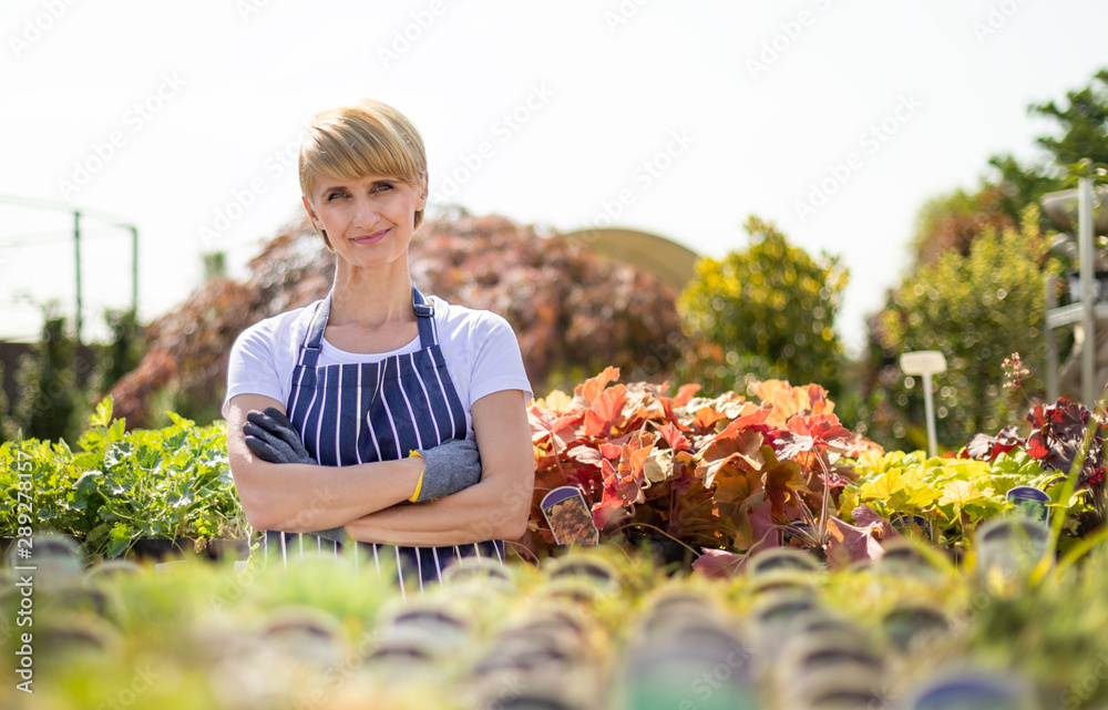 Proud gardener woman who is employee in garden center