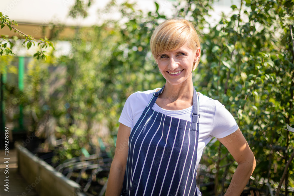 Proud gardener woman who is employee in garden center