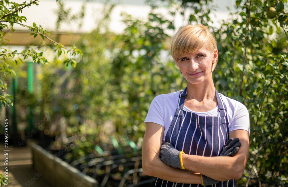 Proud gardener woman who is employee in garden center