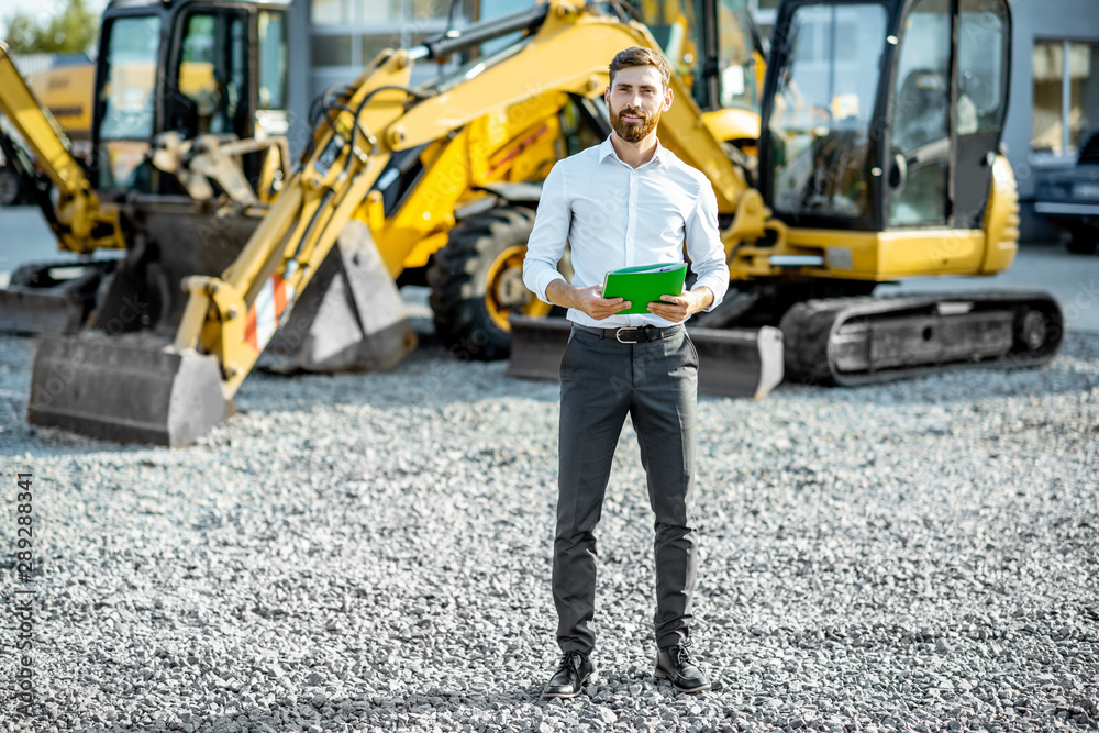 Portrait of a handsome sales consultant or manager standing on the open ground of the shop with heav