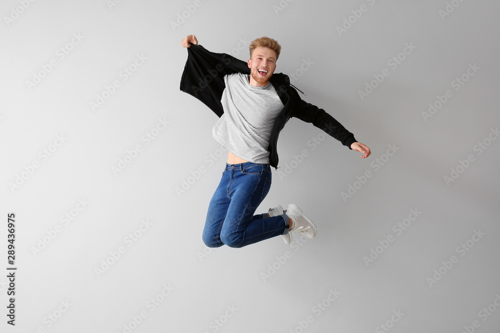 Handsome jumping young man against light background