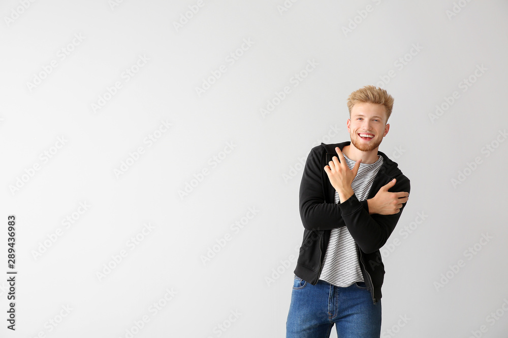 Handsome young man dancing against light background