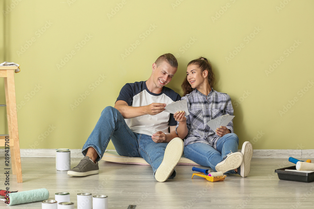 Happy young couple choosing color of walls in their new house