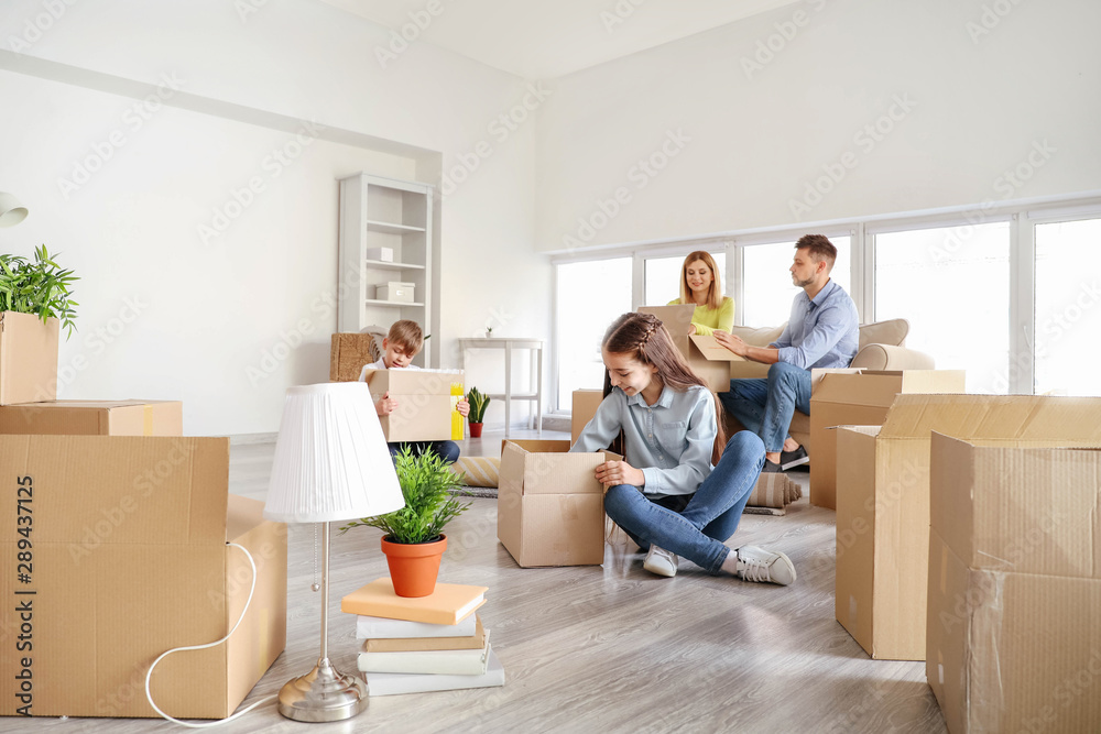 Happy family unpacking belongings in their new house