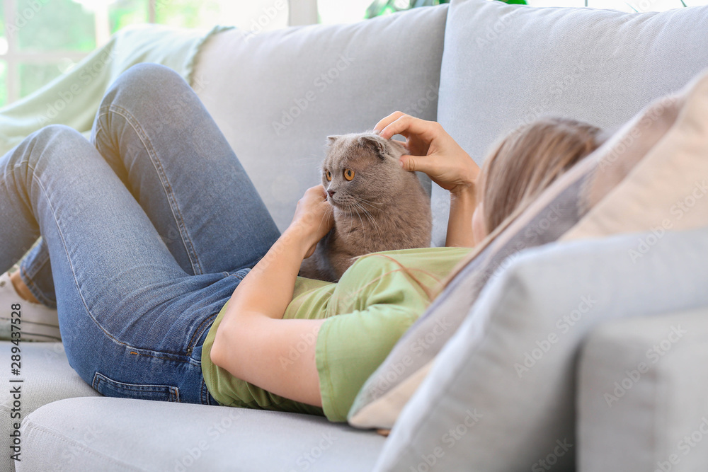 Beautiful woman with cute cat lying on sofa at home