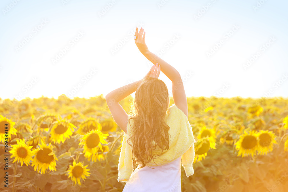 Beautiful young woman in sunflower field on summer day