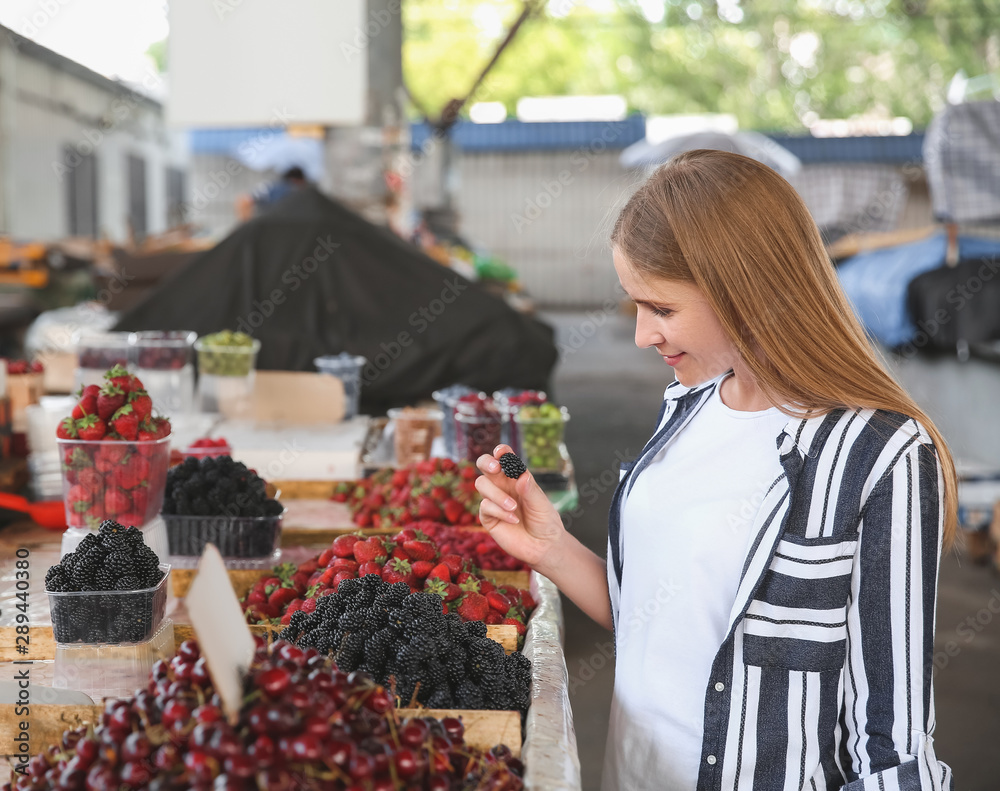 Woman choosing fresh berries at market