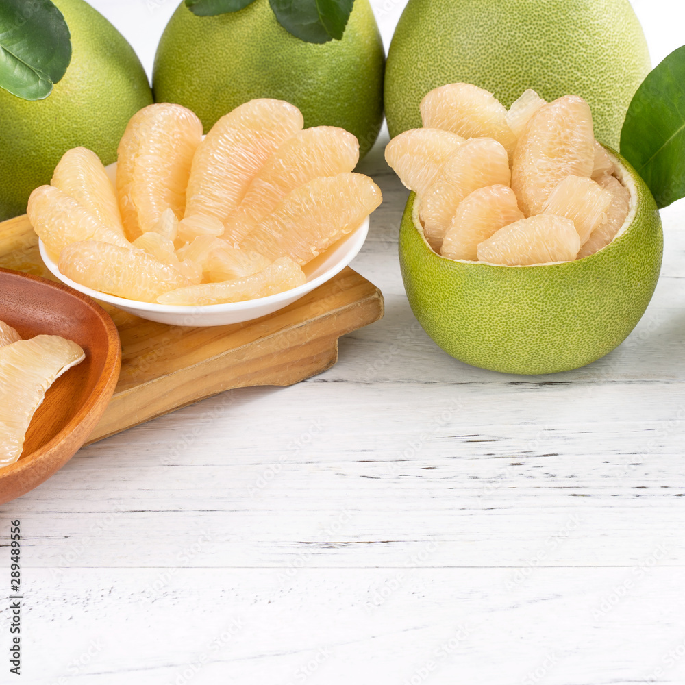 Fresh peeled pomelo, pummelo, grapefruit, shaddock on bright wooden table background. Seasonal fruit