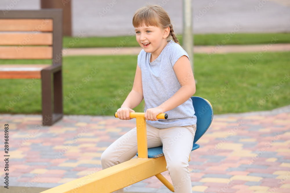 Cute little girl on seesaw in park