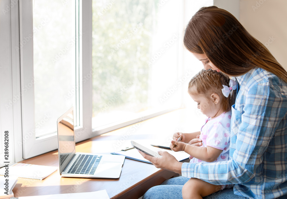 Working mother with her daughter at home