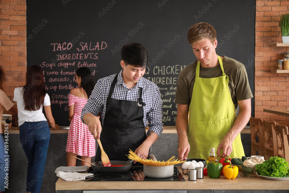 Handsome men cooking together in kitchen