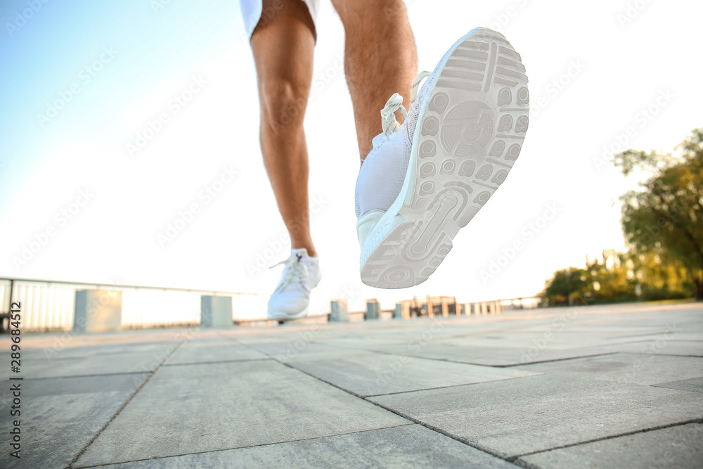 Handsome sporty man running outdoors, closeup