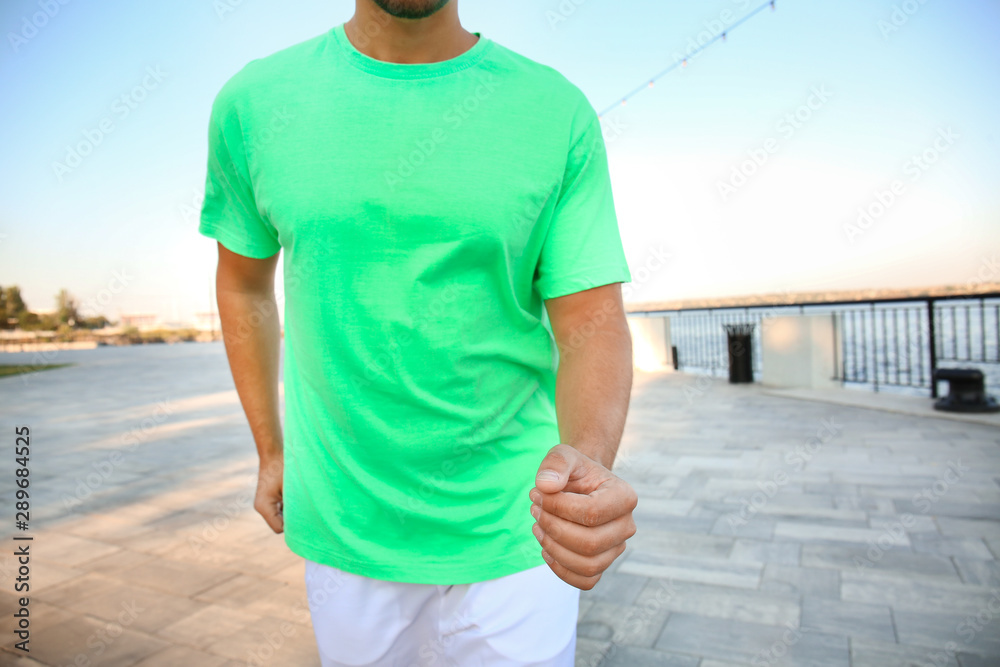 Handsome sporty man running near river