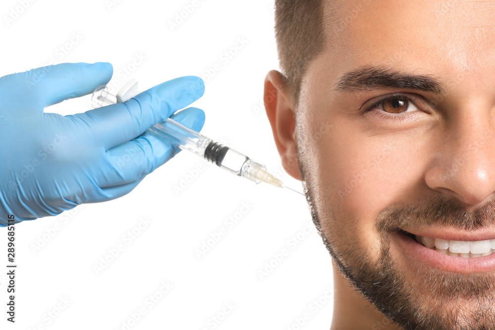 Handsome man receiving filler injection on white background, closeup