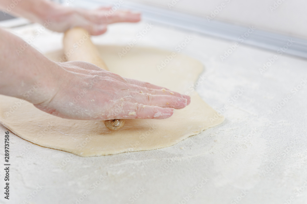 Сook rolls out the dough with rolling pin on white background. Cooking in the kitchen baking. Female