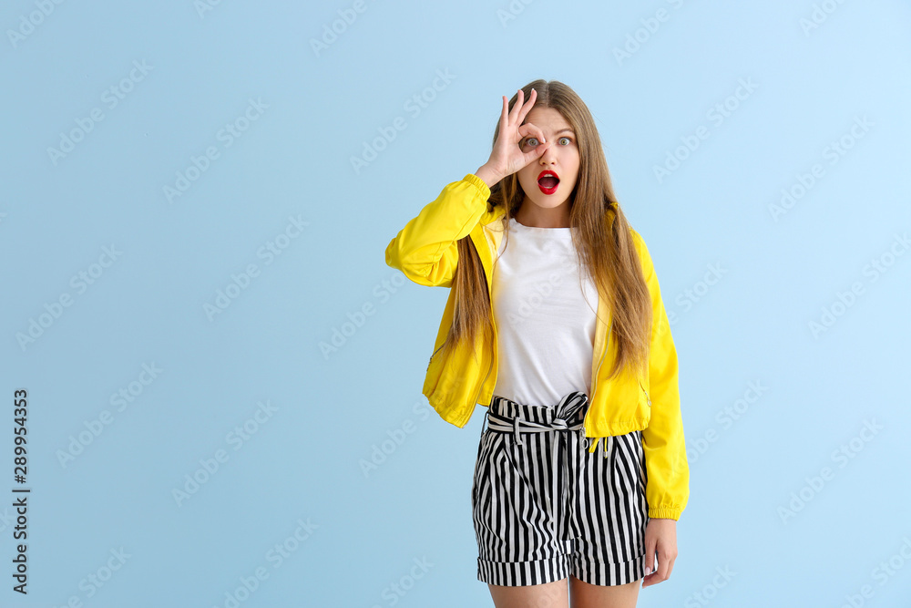 Surprised young woman on color background