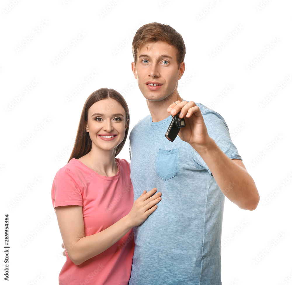 Happy young couple with key from new car on white background