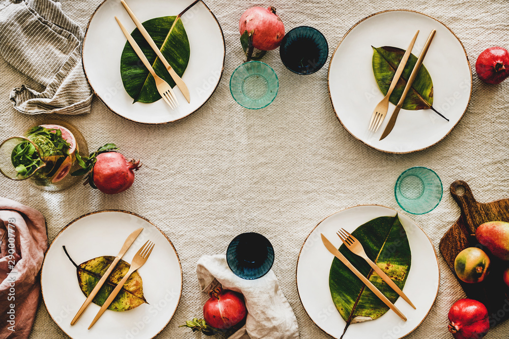 Fall or Autumn table setting for holiday dinner. Flat-lay of dinnerware with fruit and fallen leaves