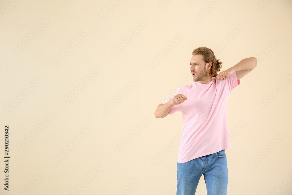 Cool young man dancing against light background