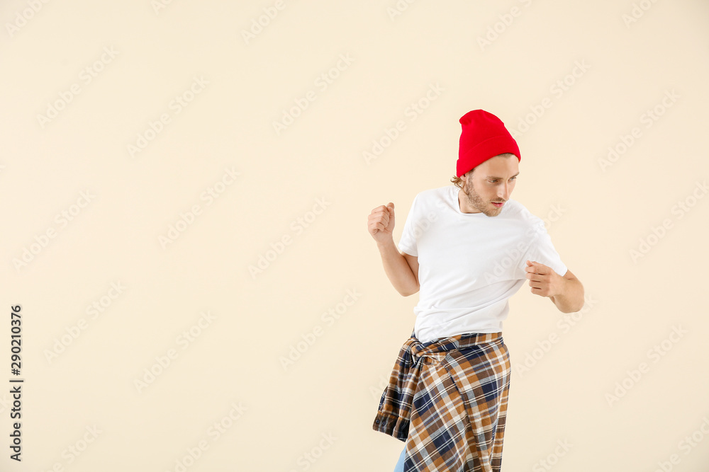 Cool young man dancing against light background