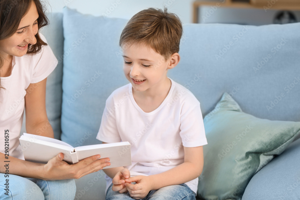 Little boy and his elder sister reading book at home