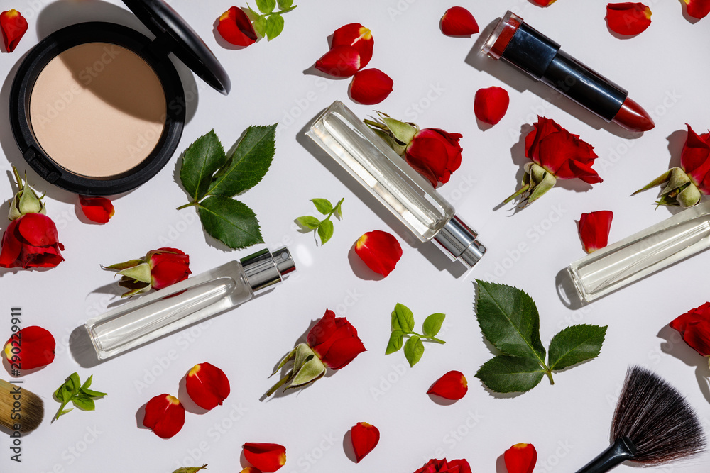 Bottles of woman perfume with cosmetic products and red roses on white background