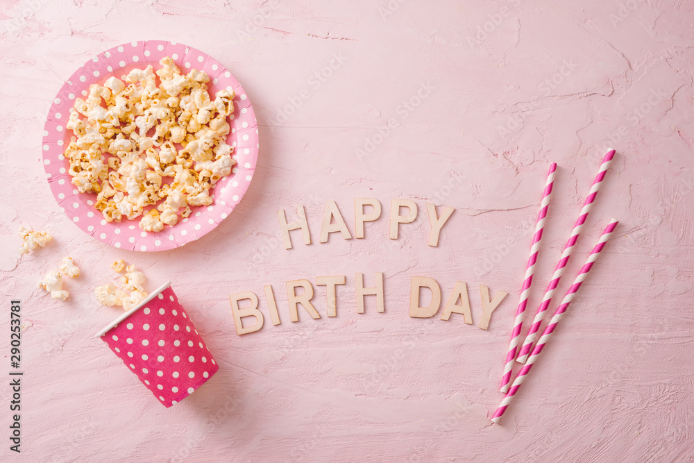 Birthday party background, border of confetti, sweets, lollipops and gift on pink surface, copy spac