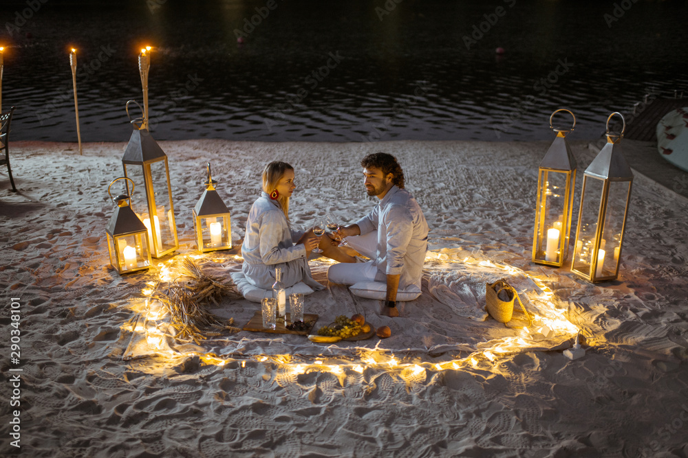 Couple having a romantic dinner at the beautifully decorated place illuminated with different lights