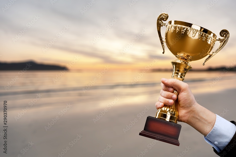 Hand holding golden trophy on blurred background