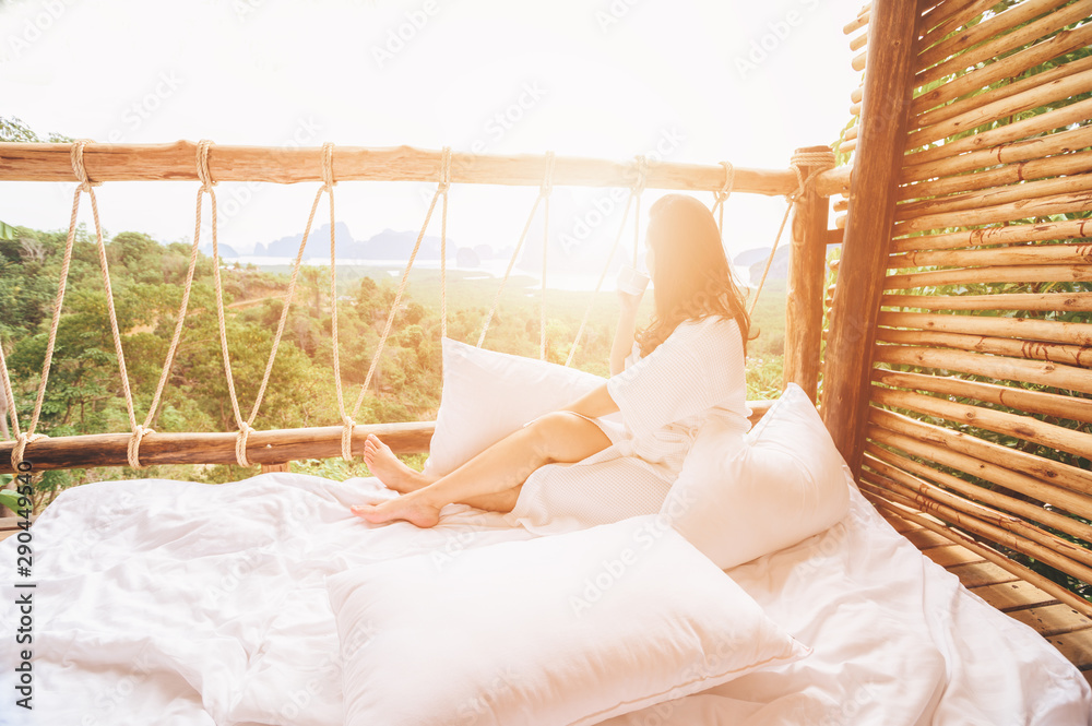 Woman in the morning holding a cup of tea or coffee and looking at the sunrise on the nature backgro