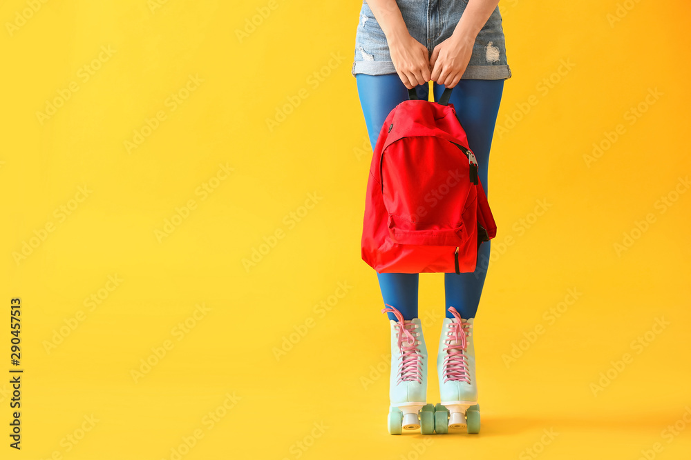 Beautiful young woman on roller skates against color background