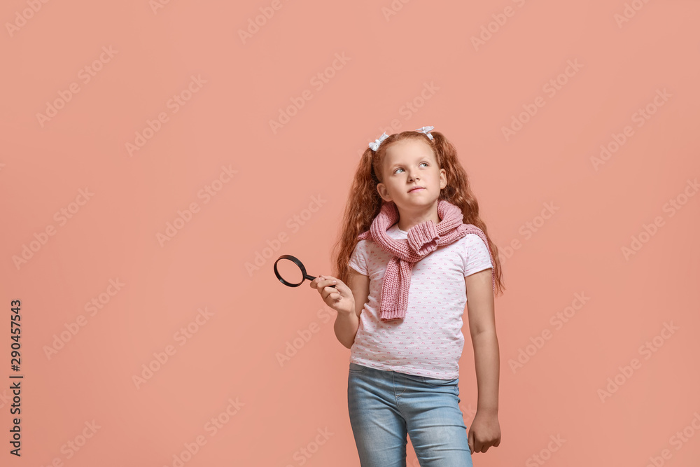 Little girl with magnifying glass on color background