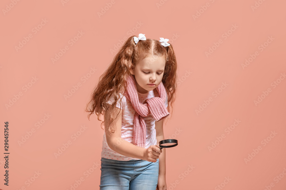 Little girl with magnifying glass on color background