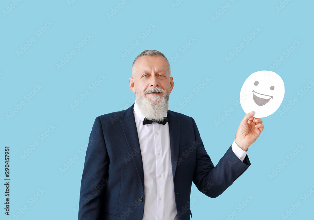 Mature man with emoticon on color background