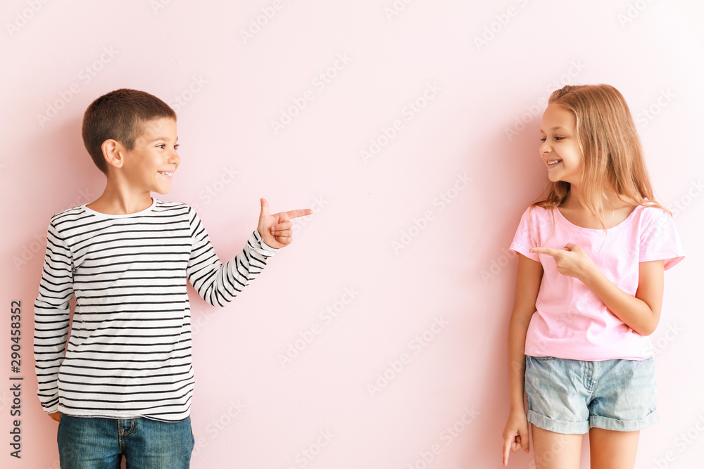 Portrait of happy little children pointing at each other on color background