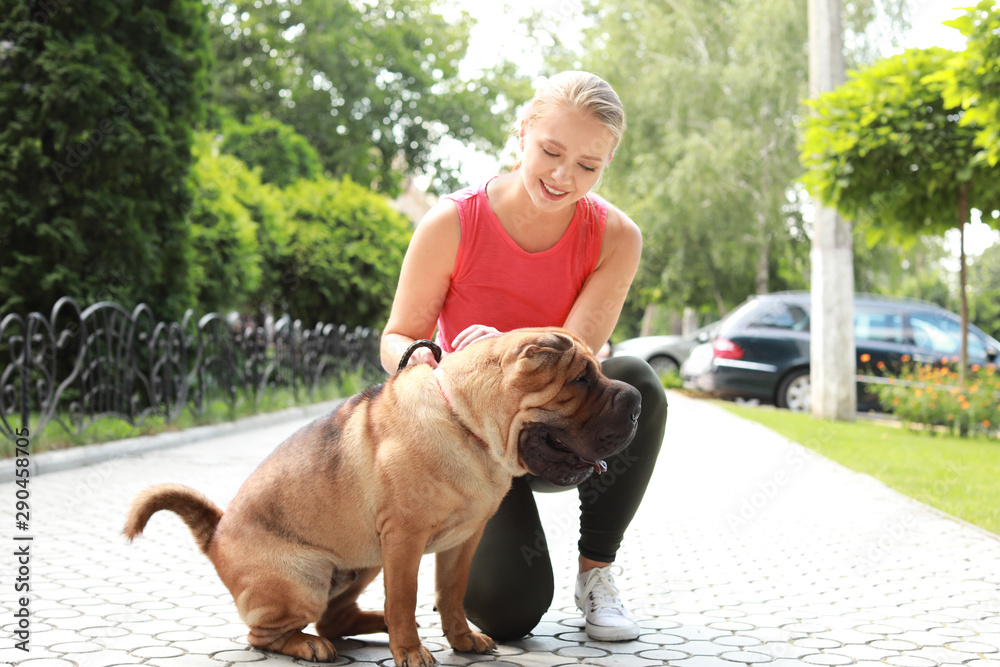 Sporty woman with cute dog walking outdoors