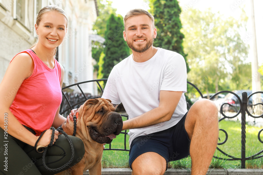 Sporty couple with cute dog walking outdoors