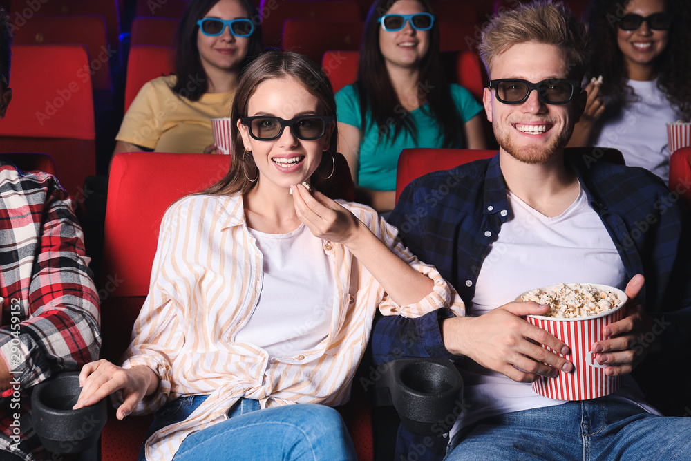 Friends with popcorn watching movie in cinema