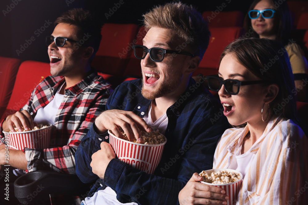 Friends with popcorn watching movie in cinema