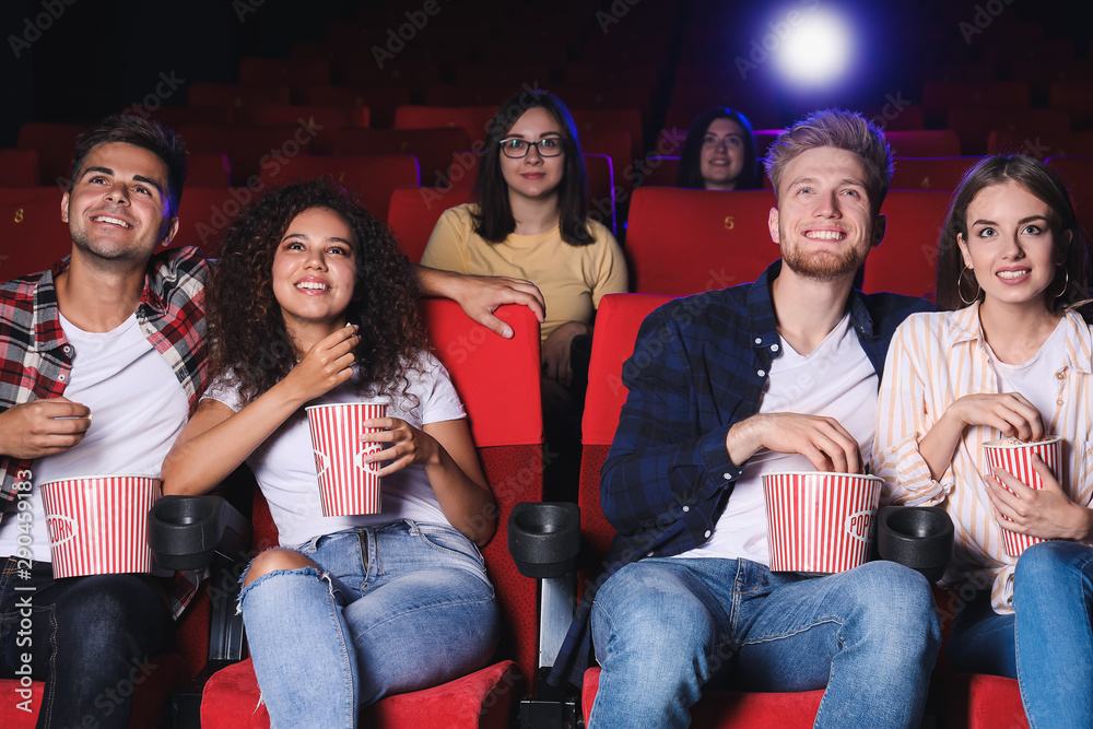 Friends with popcorn watching movie in cinema