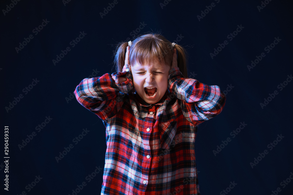 Portrait of screaming little girl on dark background