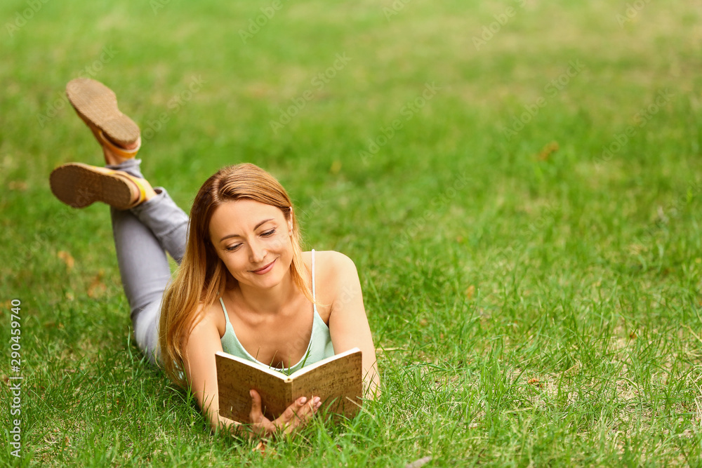 Woman reading book while relaxing in park