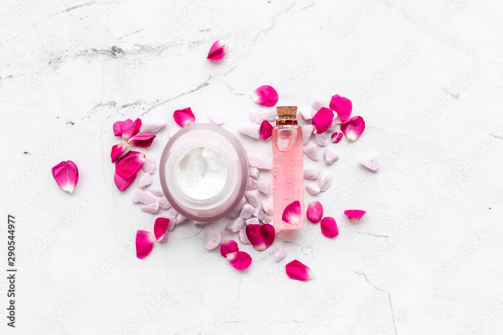 little stones and rose cosmetics on marble background top view