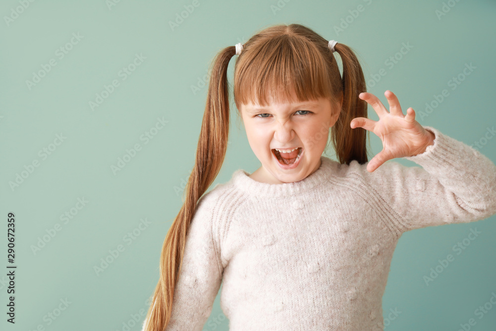 Portrait of angry little girl on color background