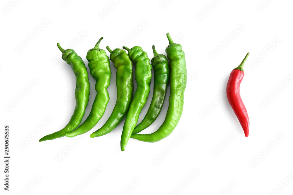 Red chili pepper and green ones on white background. Concept of uniqueness