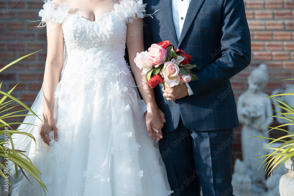 Bride and groom hold hands,Bride and groom hands with wedding rings and bridal dress.Close Up view o